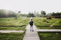 Person in Black Jacket Walking on Wooden Pathway