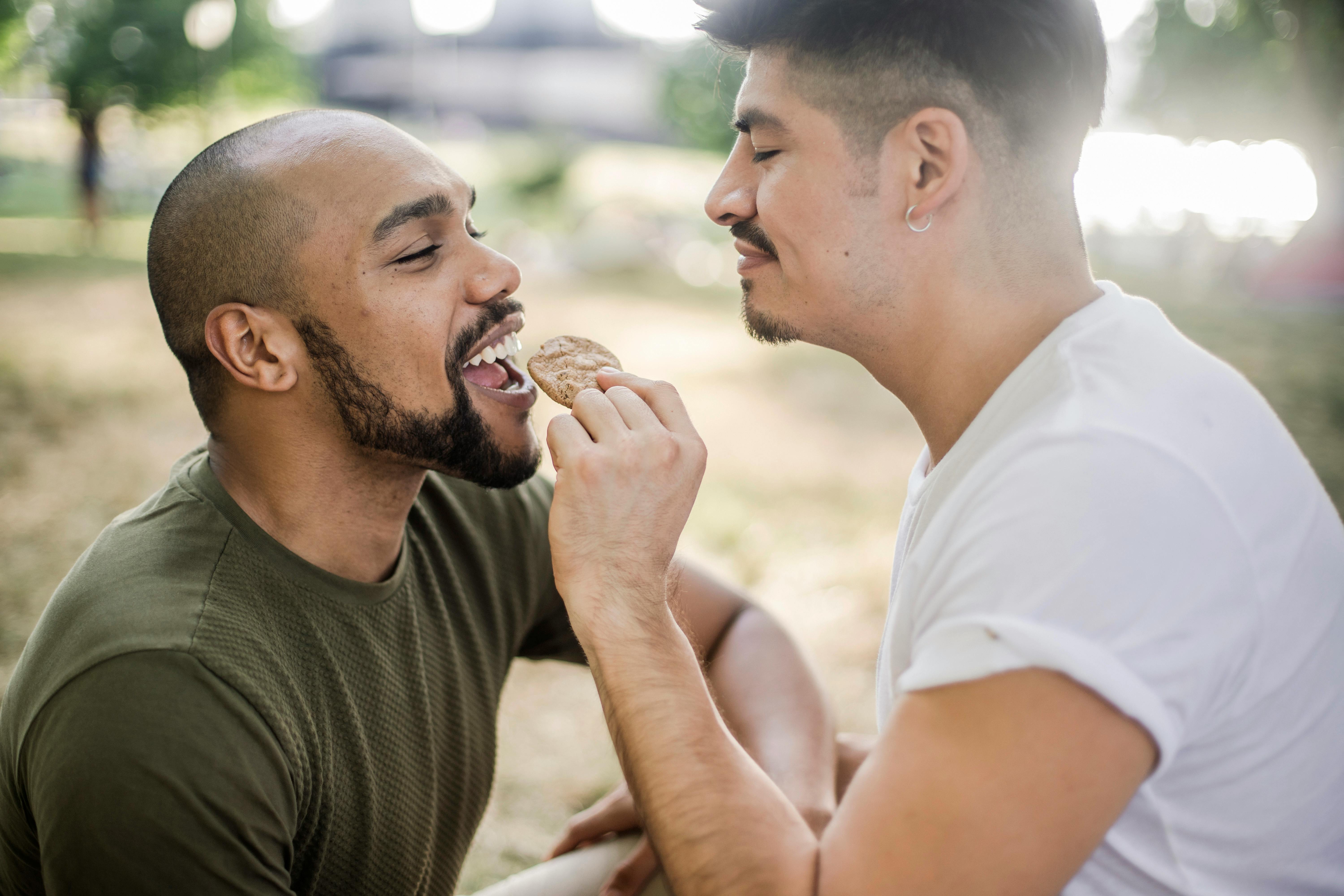 Man Feeding a Cookie To Another Man · Free Stock Photo