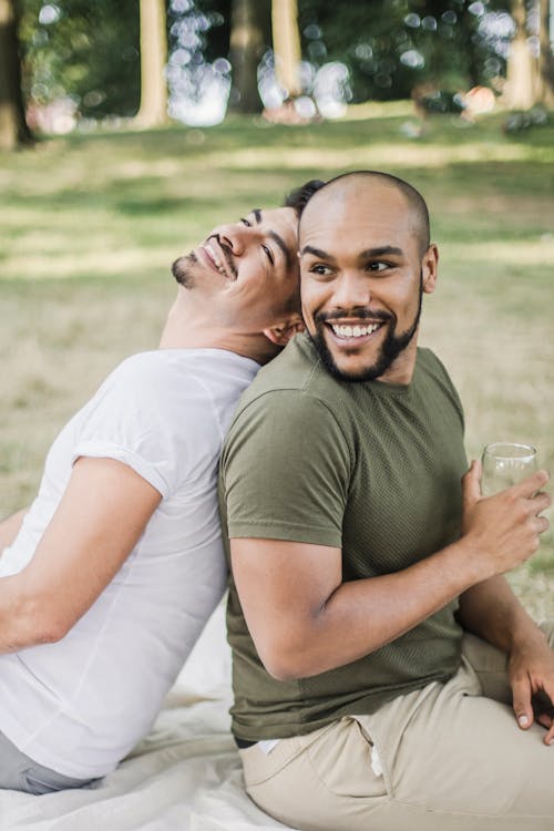 Free Two Men Sitting Back to Back and Smiling Stock Photo