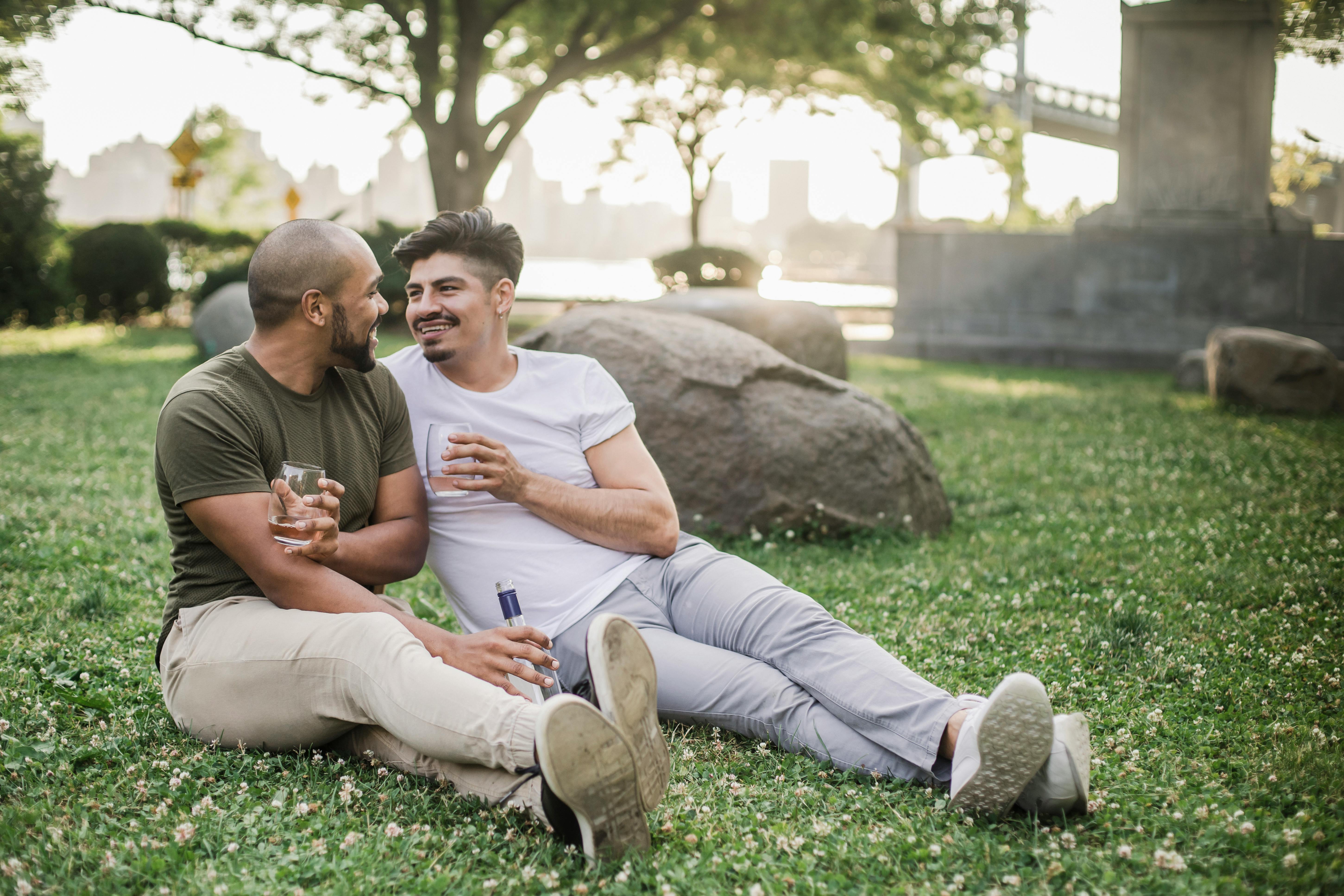 two men sitting on the grass and looking at each other