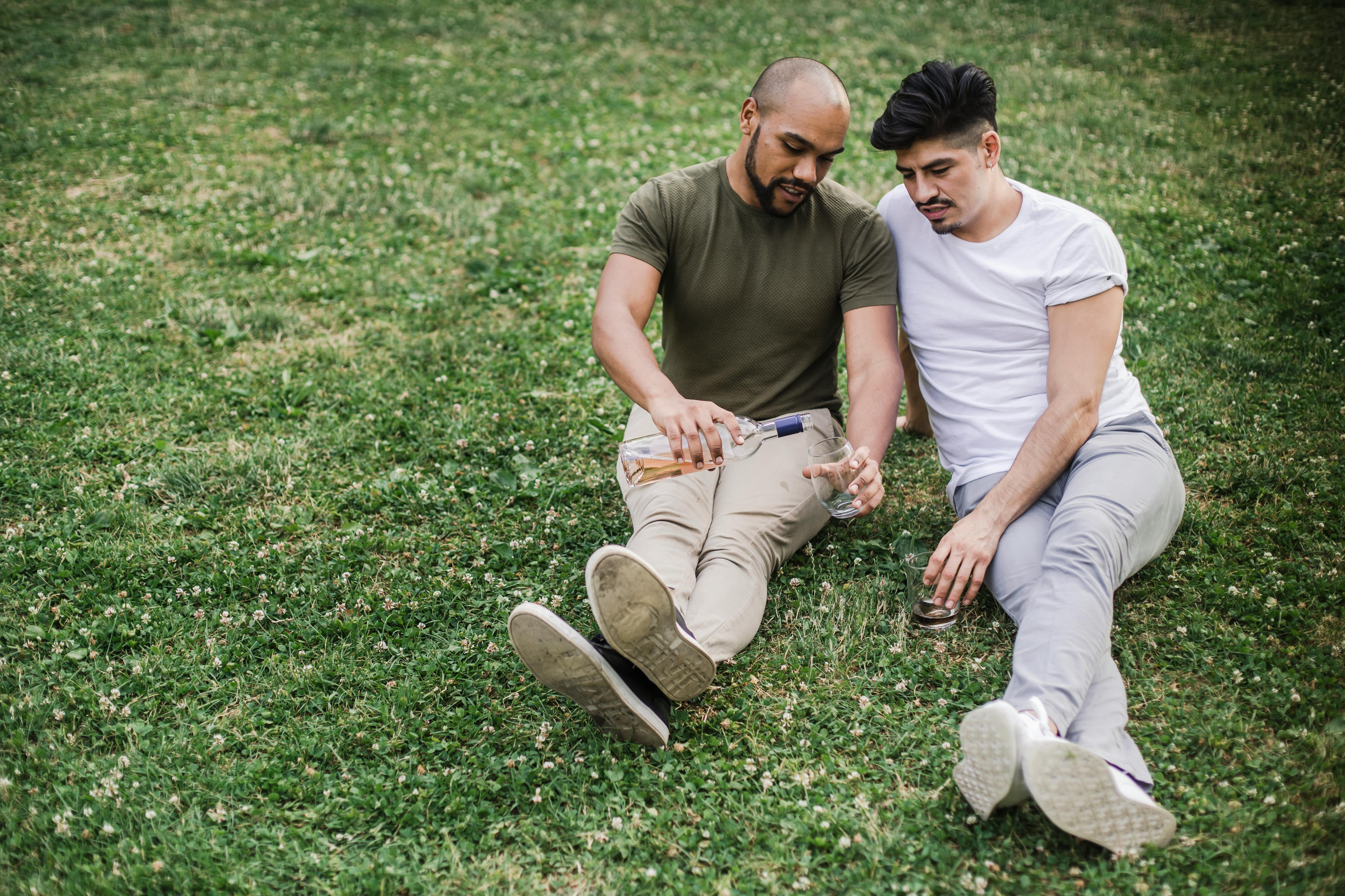 two sitting on the grass and having wine