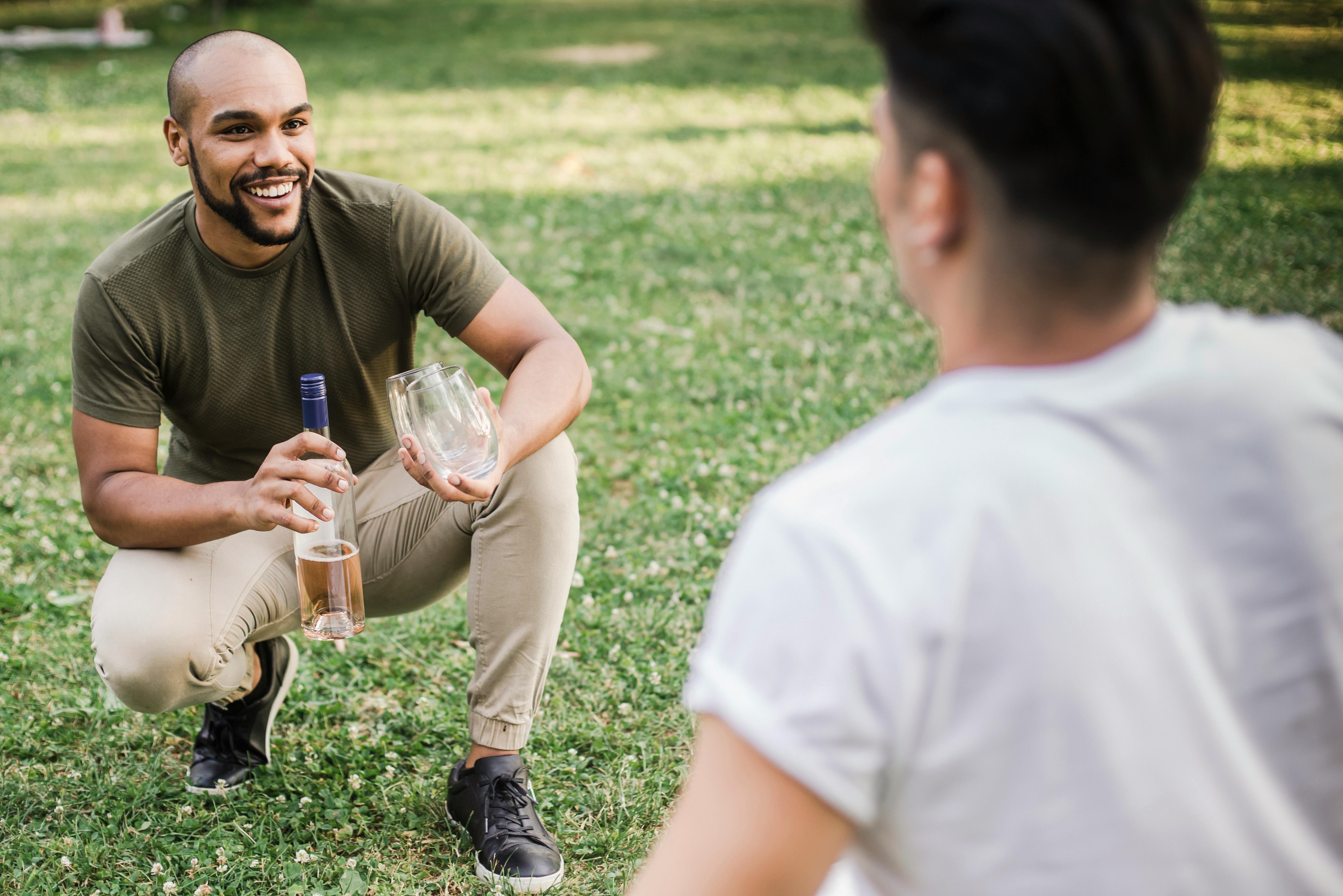 happy man kneeling and holding a wine bottle