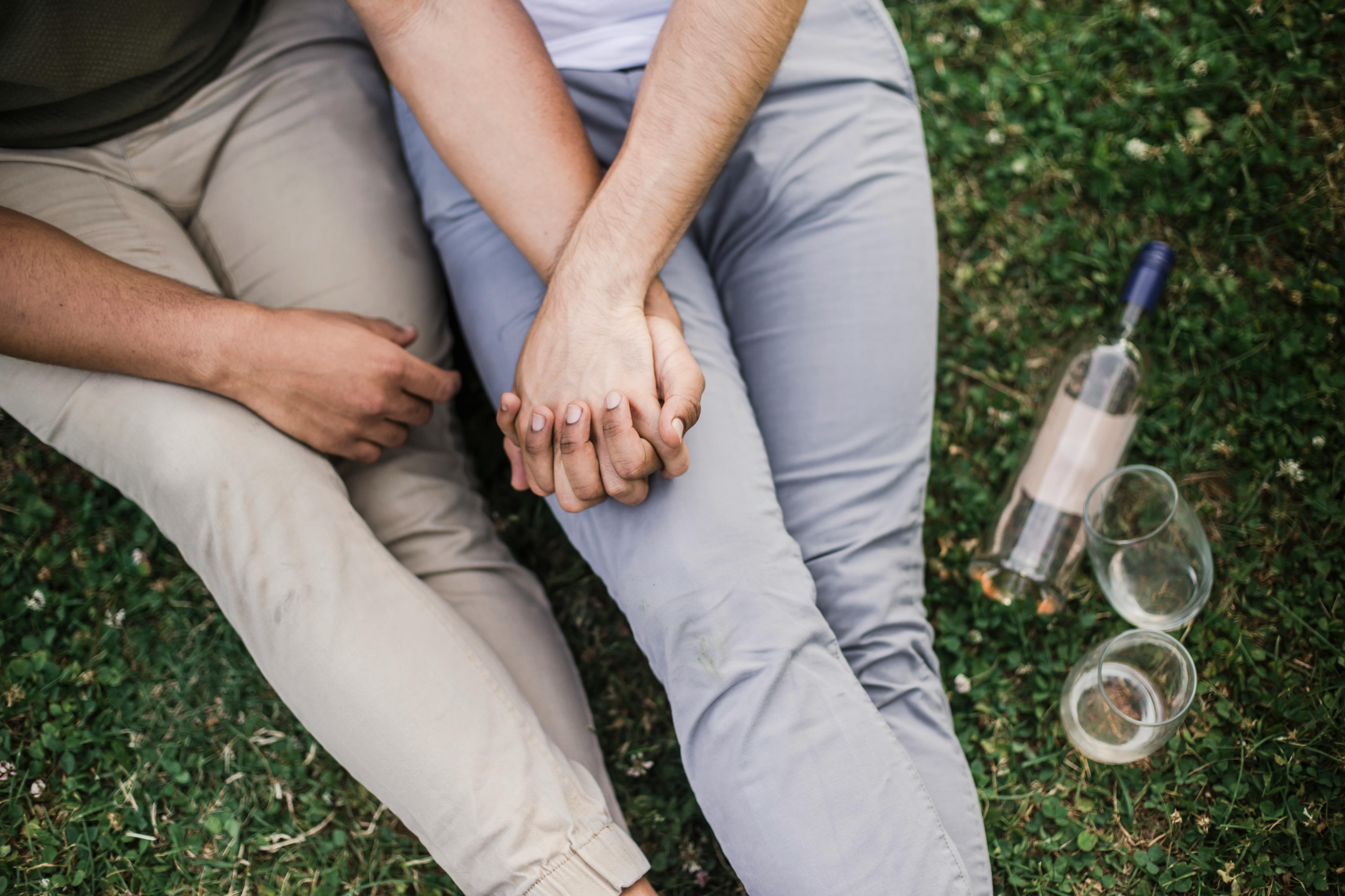 two people holding hands and sitting on the grass