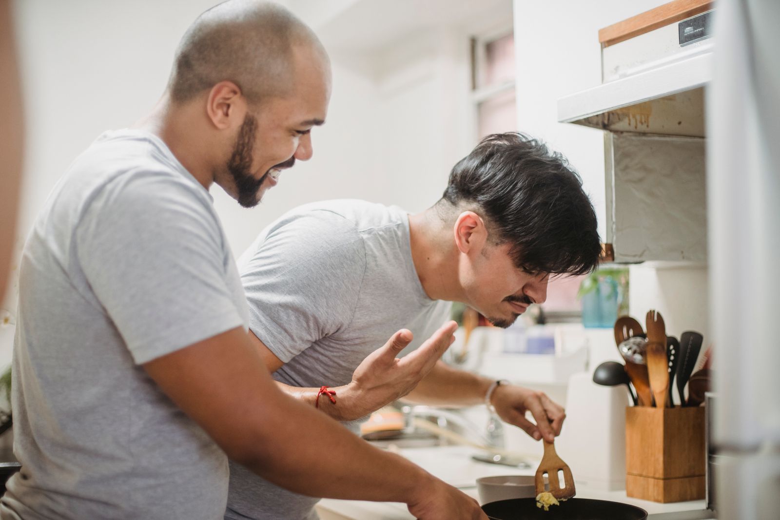 A joyful couple laughing and cooking together in a bright kitchen. Perfect for lifestyle themes.