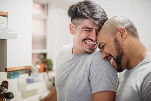 Free Happy same-sex couple enjoying a light-hearted moment in their home kitchen. Stock Photo