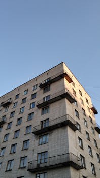 Low angle view of a brick apartment building in Sankt-Peterburg under a clear blue sky.