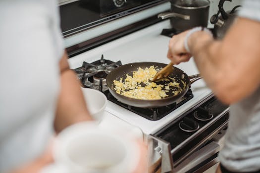 Close-up of a person cooking scrambled eggs on a stovetop, highlighting a cozy kitchen setting.