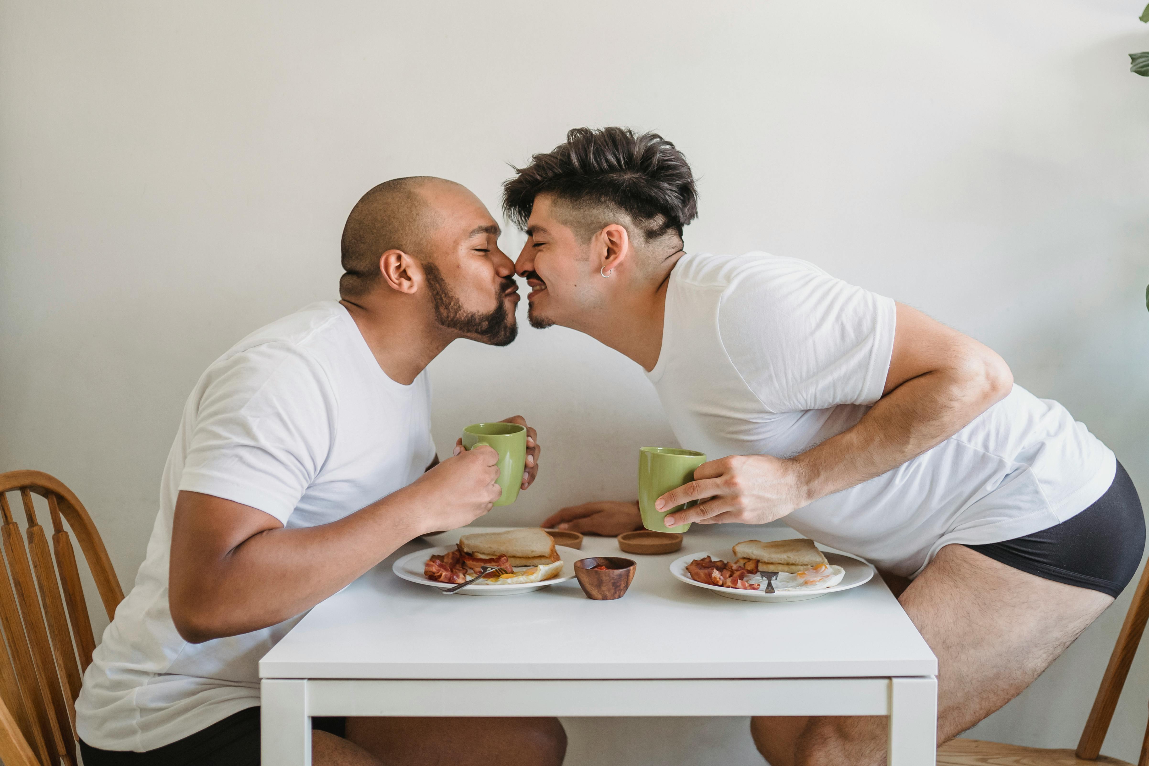 two men having breakfast and kissing