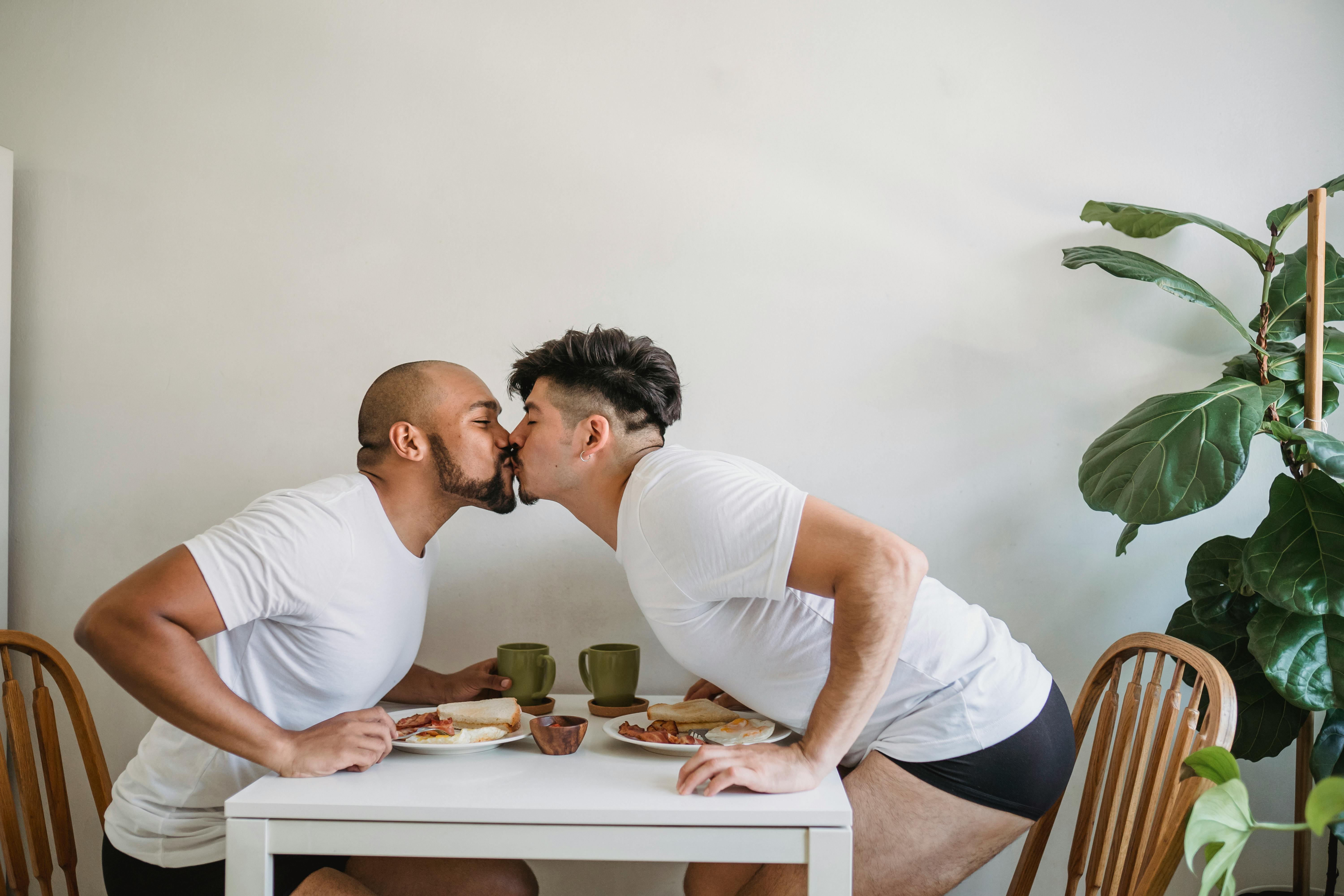 two men having breakfast and kissing