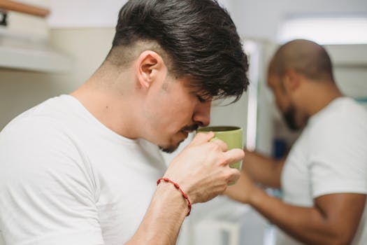 A young man enjoys morning coffee in a bright, modern kitchen setting.
