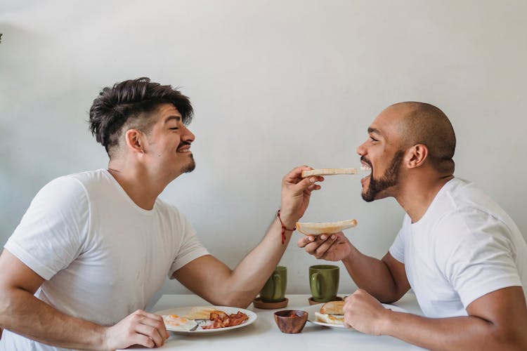 Man Giving His Partner Bite Of Slice At Breakfast