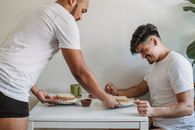 Man in White Crew Neck T-shirt and White Pants Holding White Ceramic Plate