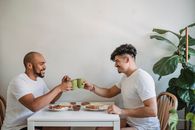 Man in White Crew Neck T-shirt Holding Green Ceramic Mug