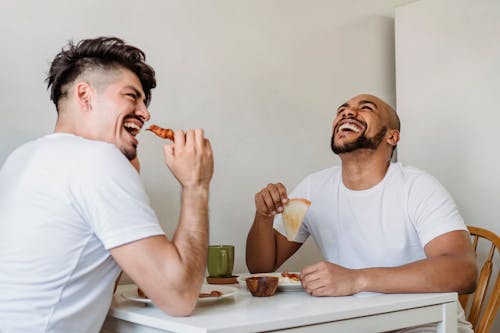 Free Men Sitting at Breakfast Table and Laughing Together Stock Photo