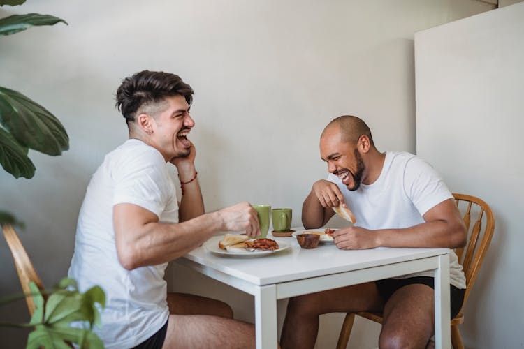 Two Friends Sitting At Table And Having Fun At Breakfast