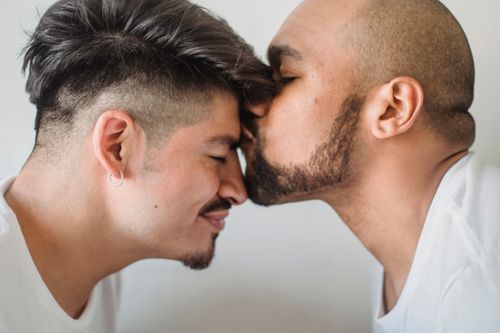 Free Close-up of an affectionate same-sex couple sharing an intimate moment in a warm setting. Stock Photo