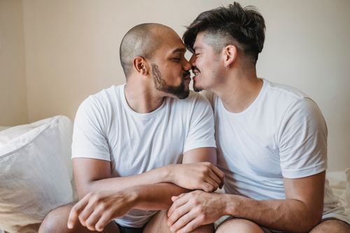Free Loving moment between a same-sex couple sitting indoors, showcasing intimacy and joy. Stock Photo