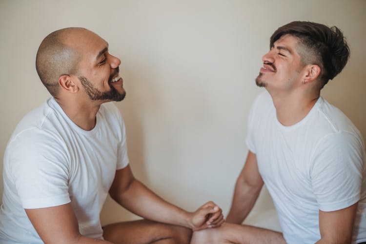 Two Men Sitting Opposite Each Other And Smiling