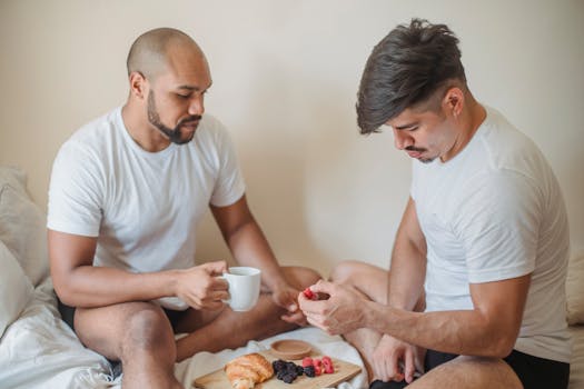Couple enjoying a romantic breakfast in bed with croissants and berries.