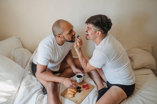 Free Man Feeding Partner for Fun at Breakfast in Bed Stock Photo