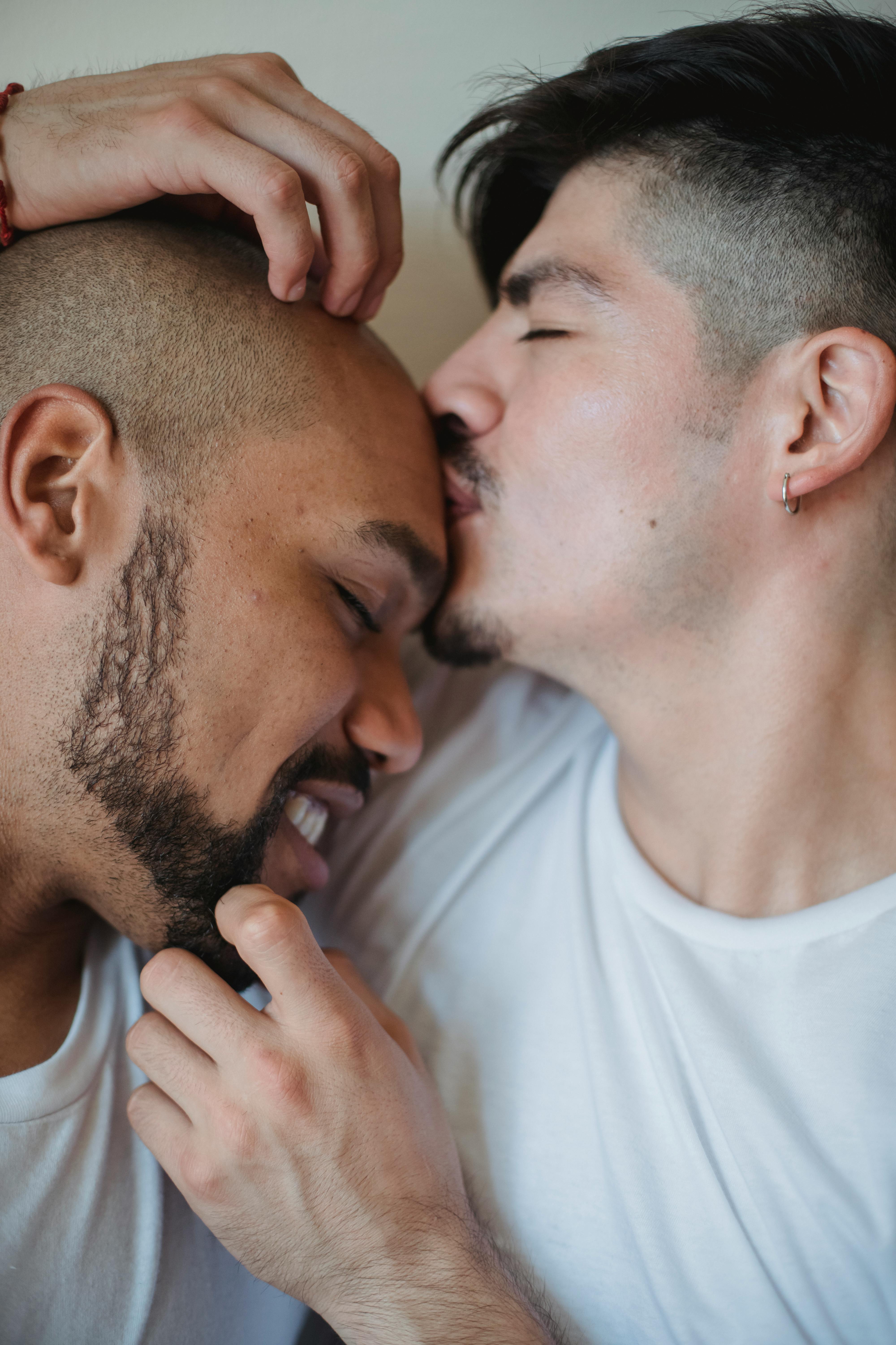 man kissing another man on the forehead