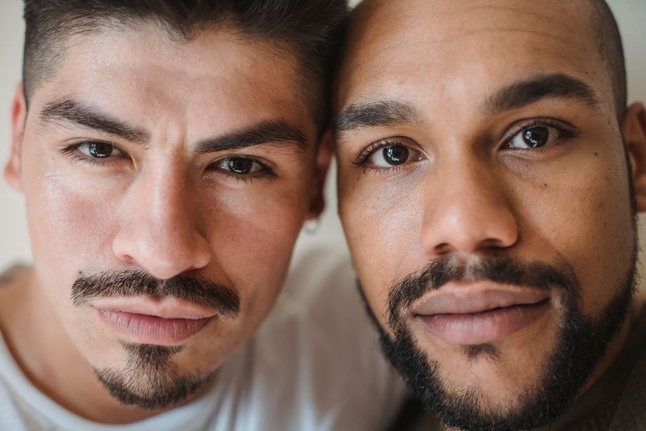 Intimate close-up portrait of two diverse men expressing thoughtful contemplation.
