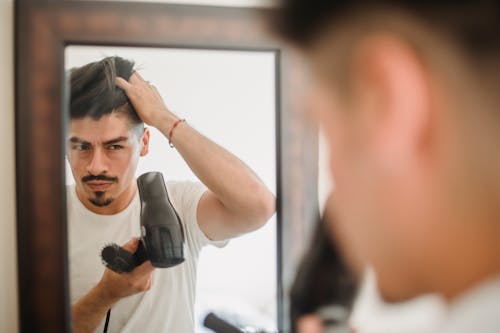 Man Drying Hair with Hairdryer in Mirror