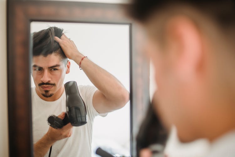 Man Drying Hair With Hairdryer In Mirror