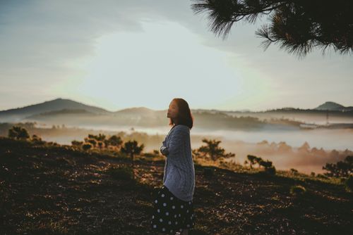 Free Asian woman enjoying a tranquil sunset in misty Dauat landscape, evoking peace and contemplation. Stock Photo