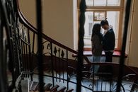 一对夫妇在复古楼梯的窗前温柔相依，这温馨一刻象征着浪漫与亲密