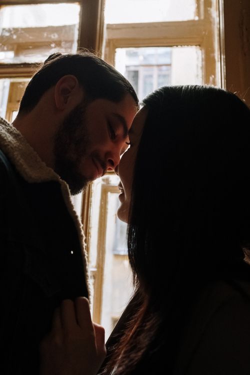 Free Silhouette of a couple sharing an intimate moment indoors by the window. Stock Photo