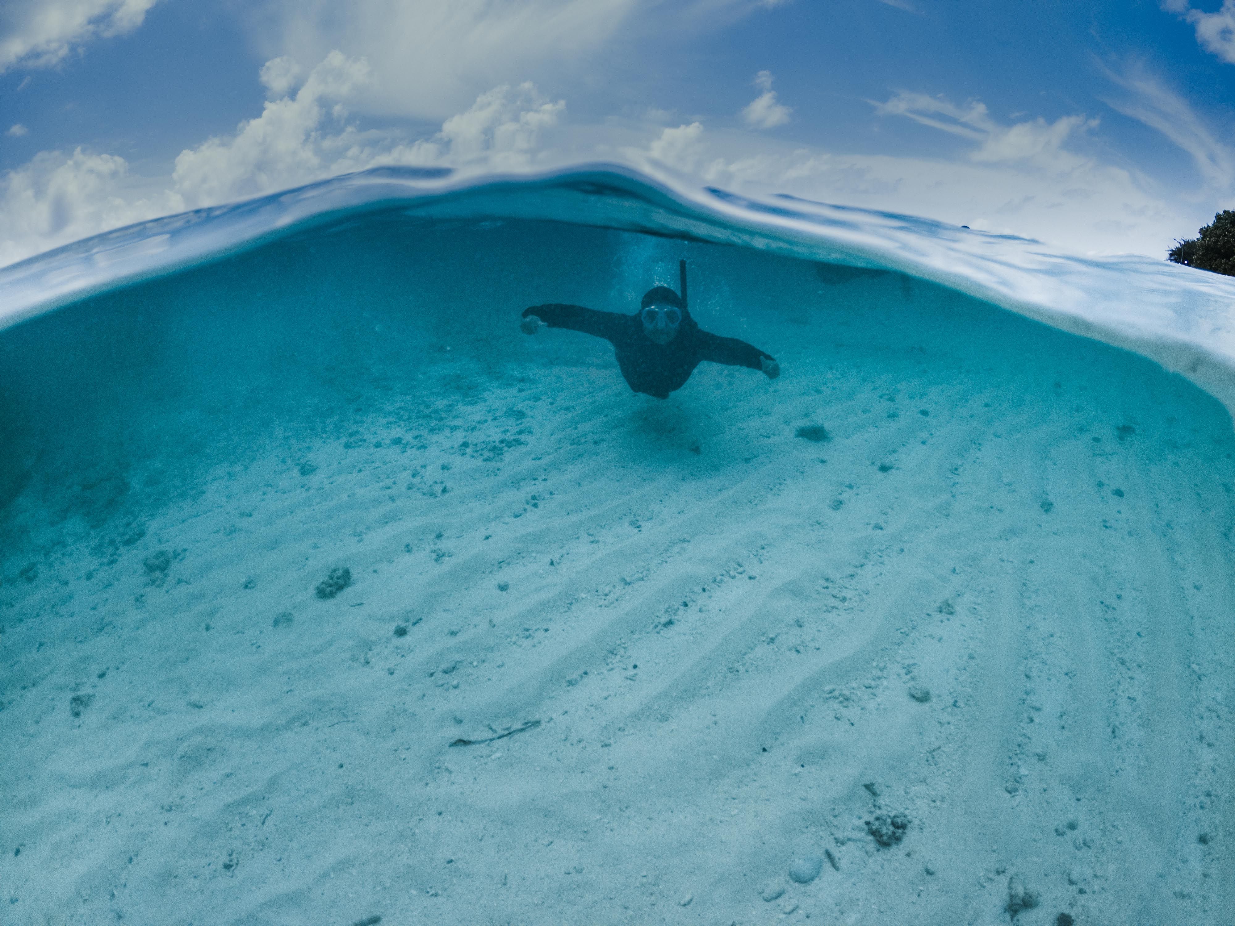 A snorkeler explores the clear, turquoise waters of the Maldives, showcasing underwater beauty. A snorkeler explores the clear, turquoise waters of the Maldives, showcasing underwater beauty.