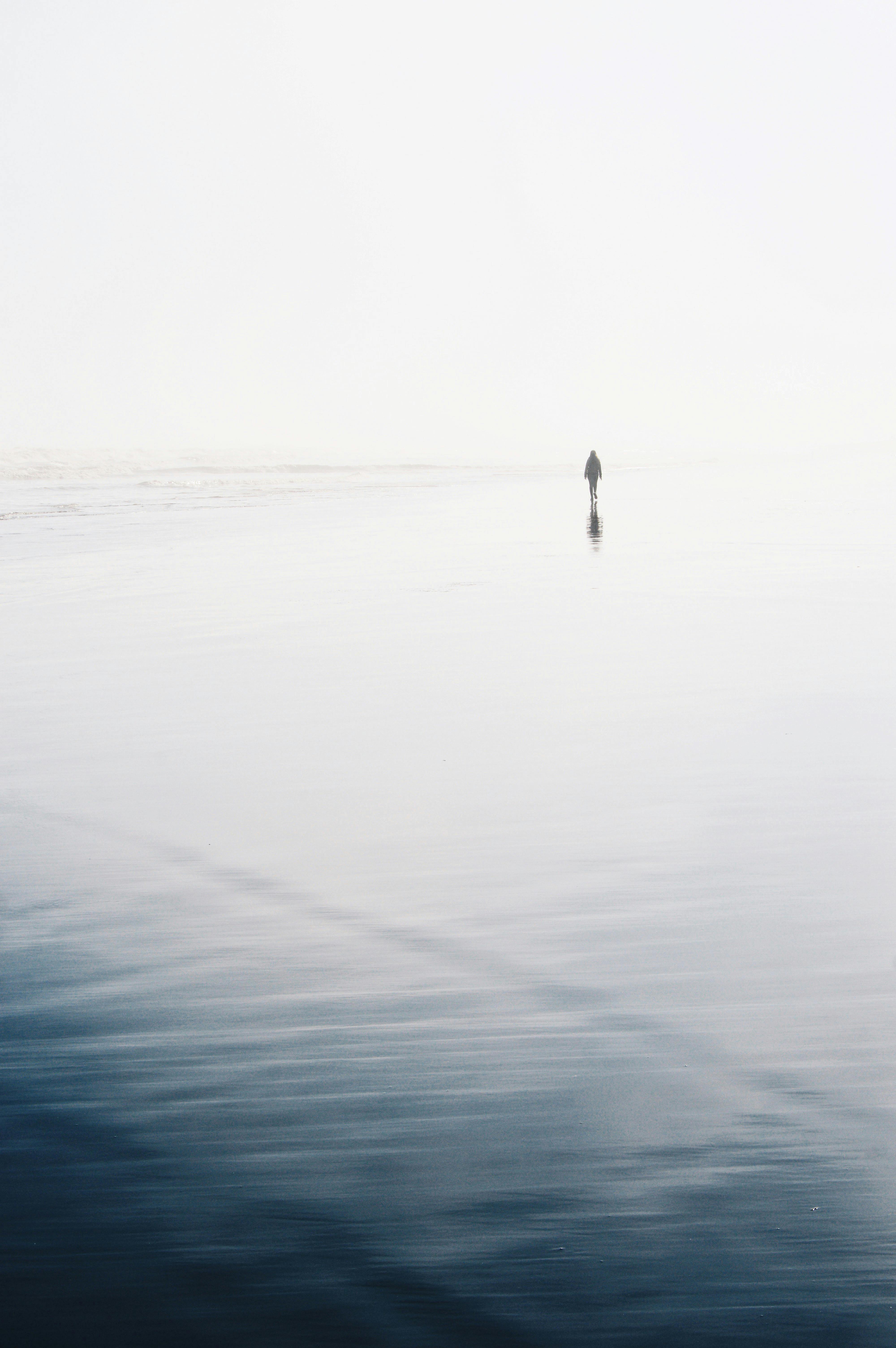 A lone figure walks along a serene Chilean beach, creating a minimalist seascape scene.