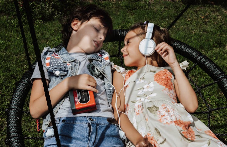 Content Kids Listening To Music On Swing