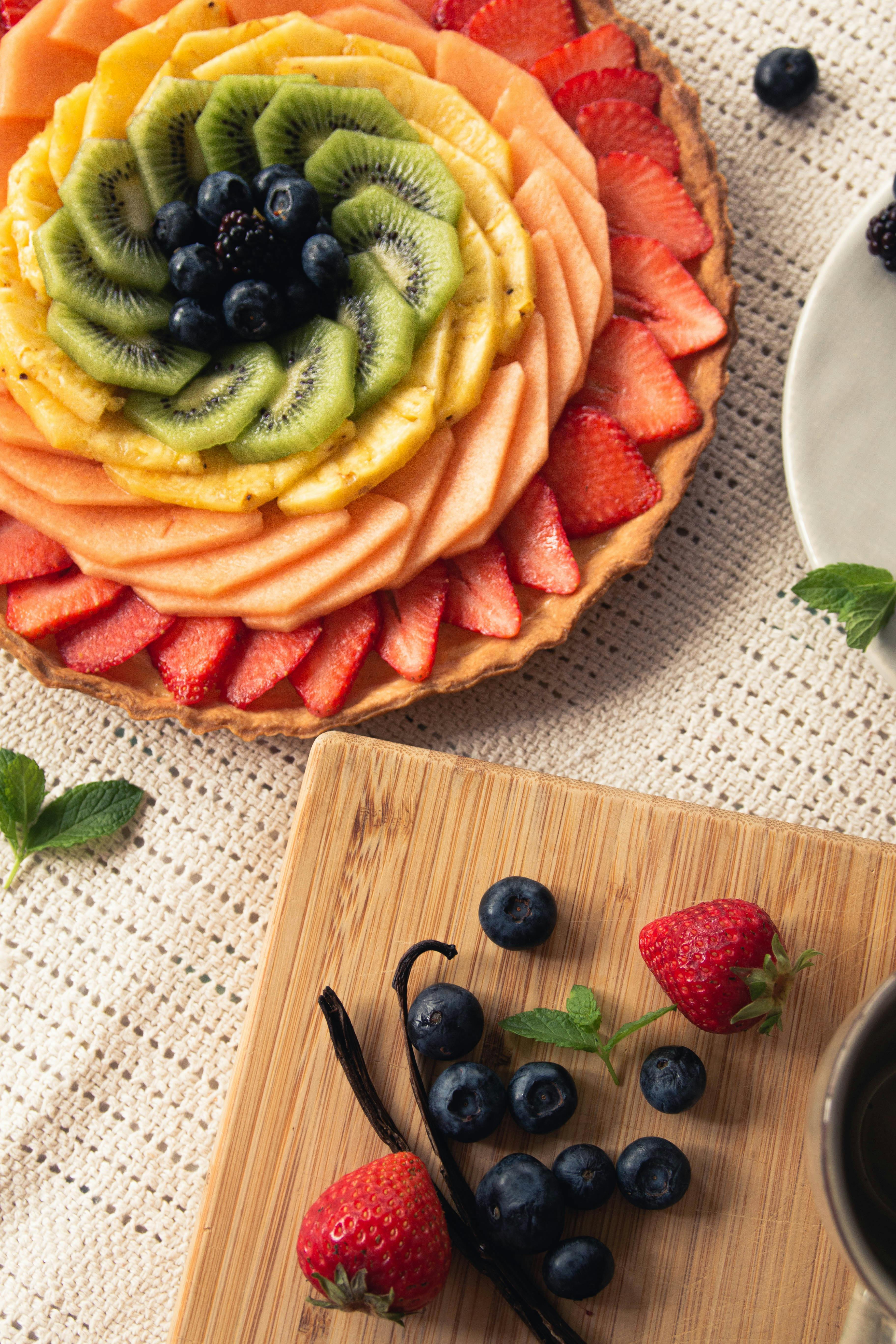 Delicious fruit tart with kiwi, berries, and melons arranged artfully for food photography.