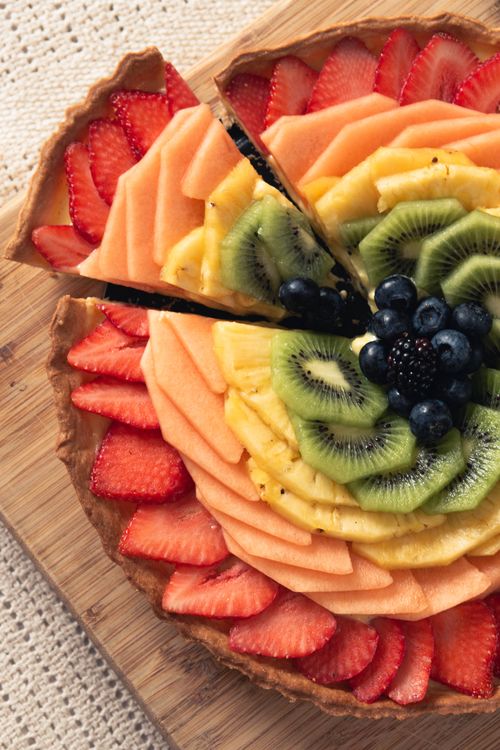 Free Colorful fruit tart with strawberries, kiwi, and berries on a wooden board, perfect for dessert. Stock Photo