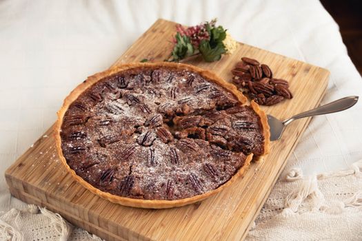 Mouth-watering homemade pecan pie with a slice missing, presented on a wooden board.