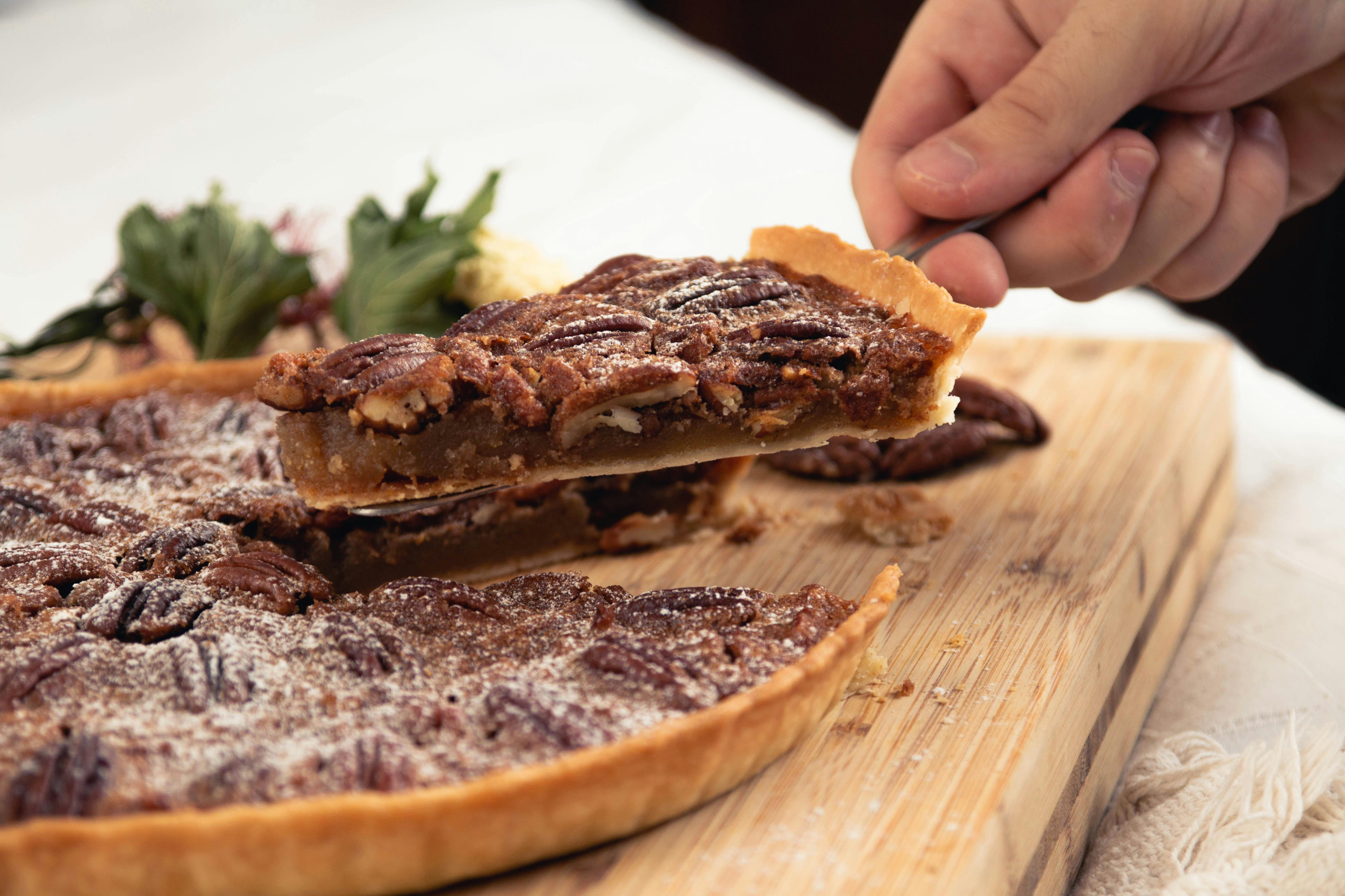 A Hand Holding a Sliced of Pecan Pie · Free Stock Photo