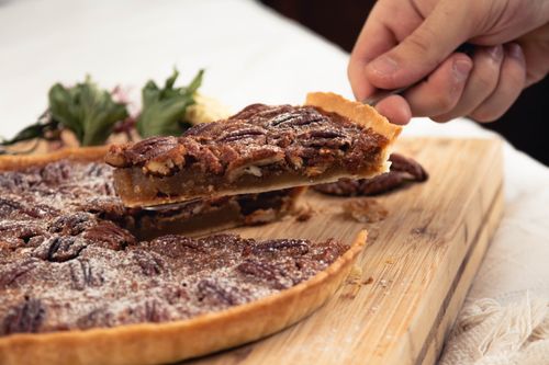 Free Close-up of a homemade pecan pie slice being removed on a wooden board. Stock Photo