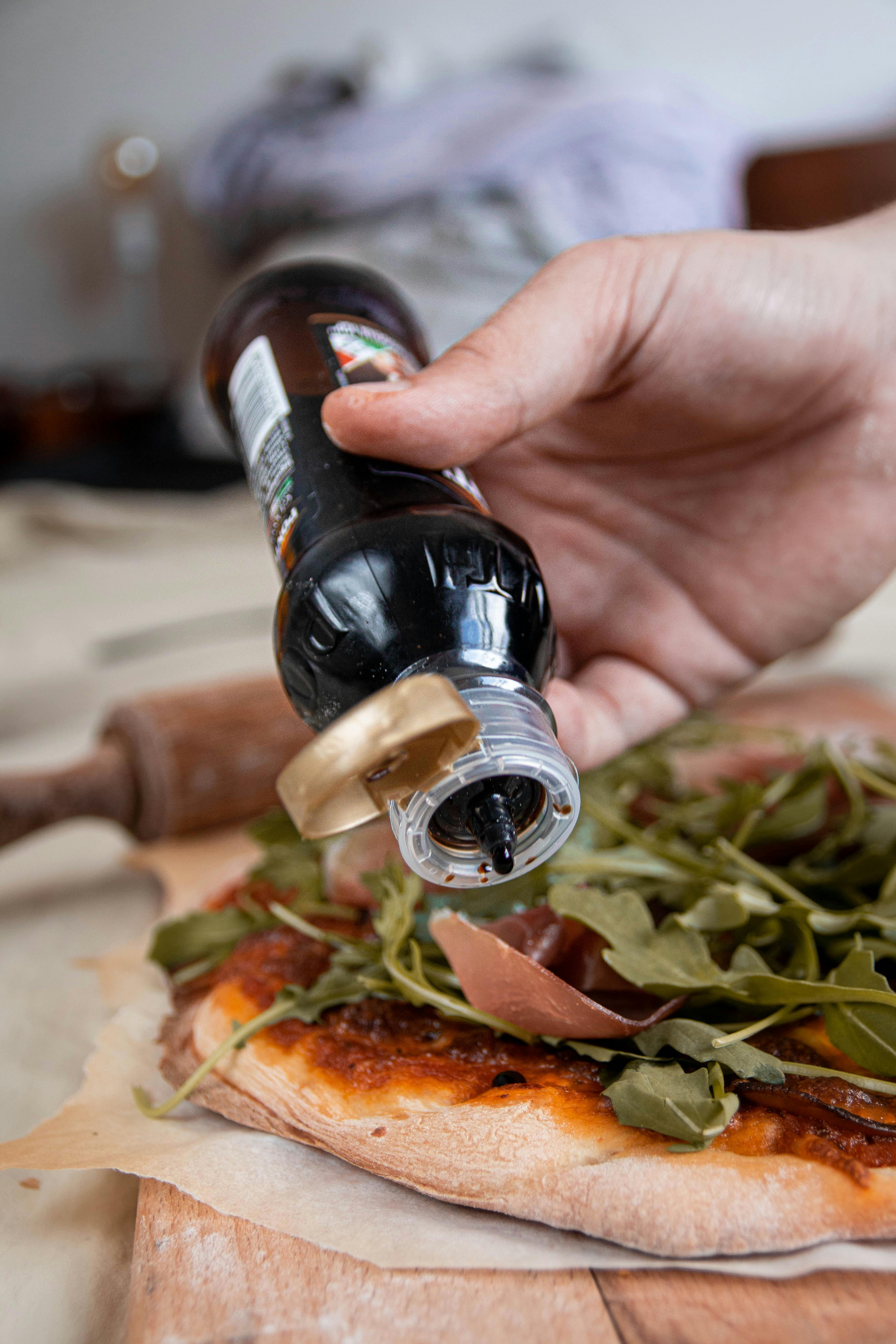 A Person Putting Balsamic Vinegar on Pizza · Free Stock Photo