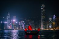 香港的天际线在夜间被点亮，以摩天大楼和传统的垃圾船为特色