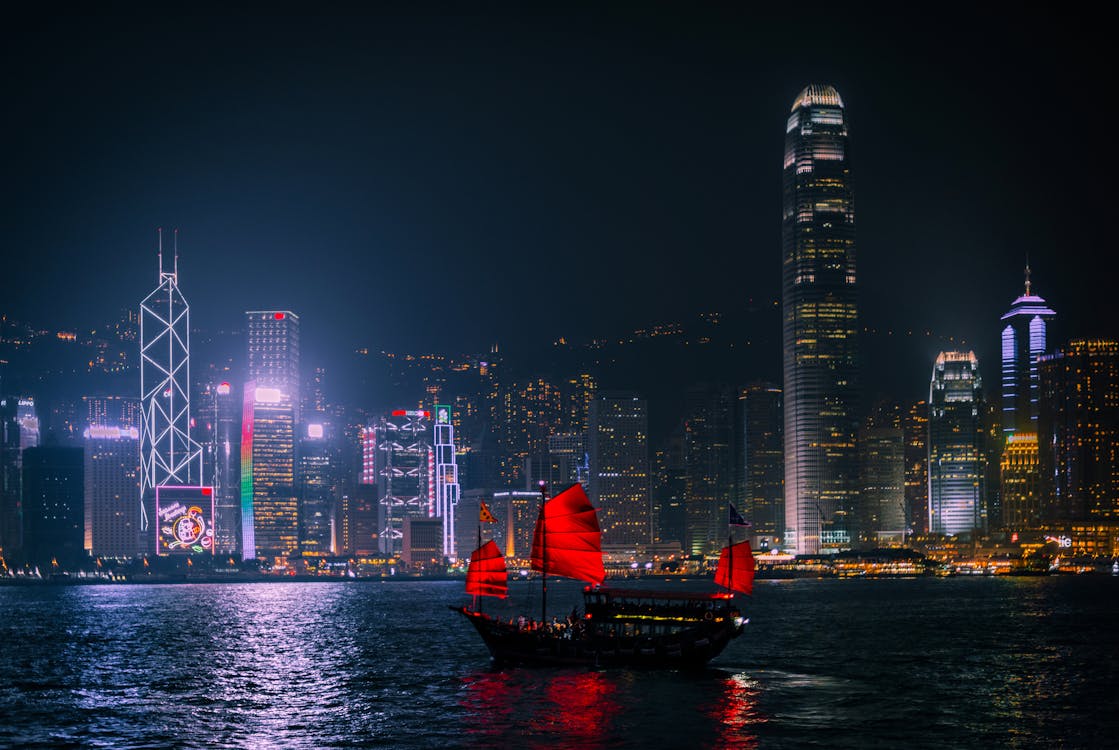 Man in Red Hoodie Standing on Boat during Night Time