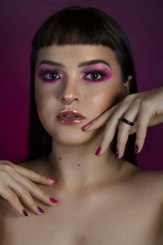 Stunning portrait of a woman with vibrant pink eyeshadow and glossy lips, shot in a studio setting.