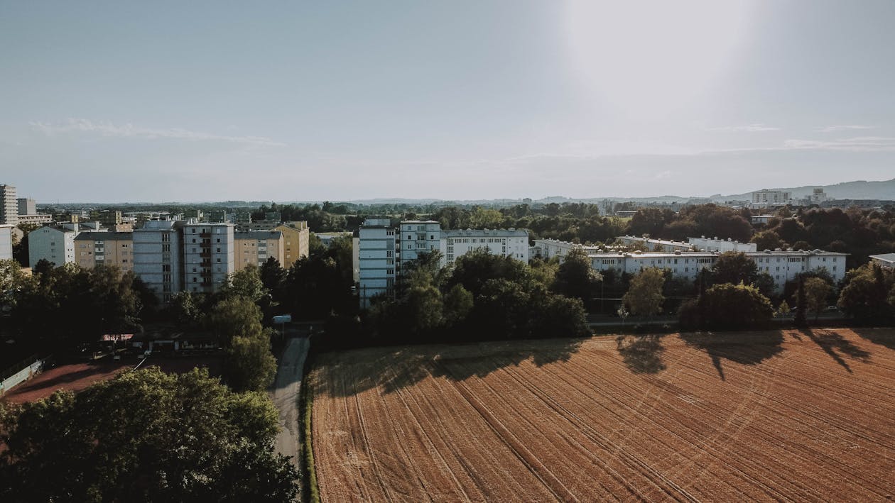 Drone view of small town with plantation and lush greenery under foggy sky