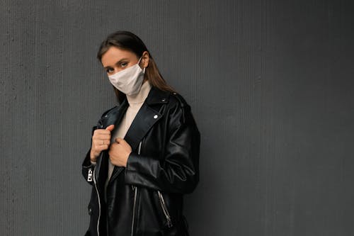 A Woman Wearing a Black Leather Jacket and a Face Mask