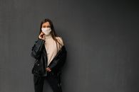 Woman in Black Leather Jacket and Black Pants Standing Beside Black Wall