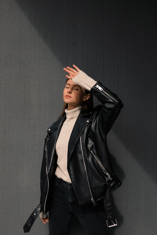 A Woman in Black Leather Jacket Standing Near Gray Wall