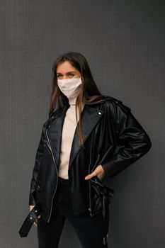 一位时尚女士在室内穿着皮夹克、戴着口罩摆姿势，既凸显现代风格，又兼顾安全性