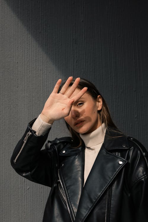 Woman in Black Leather Jacket Covering Her Face With Her Hands