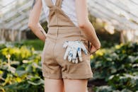 花园里，一名穿着工作服的妇女，口袋里放着花卉手套